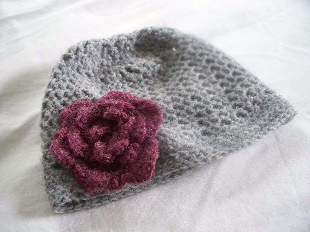 Gray crocheted hat with a pink crochet flower, for the crochet hat size chart and calculator