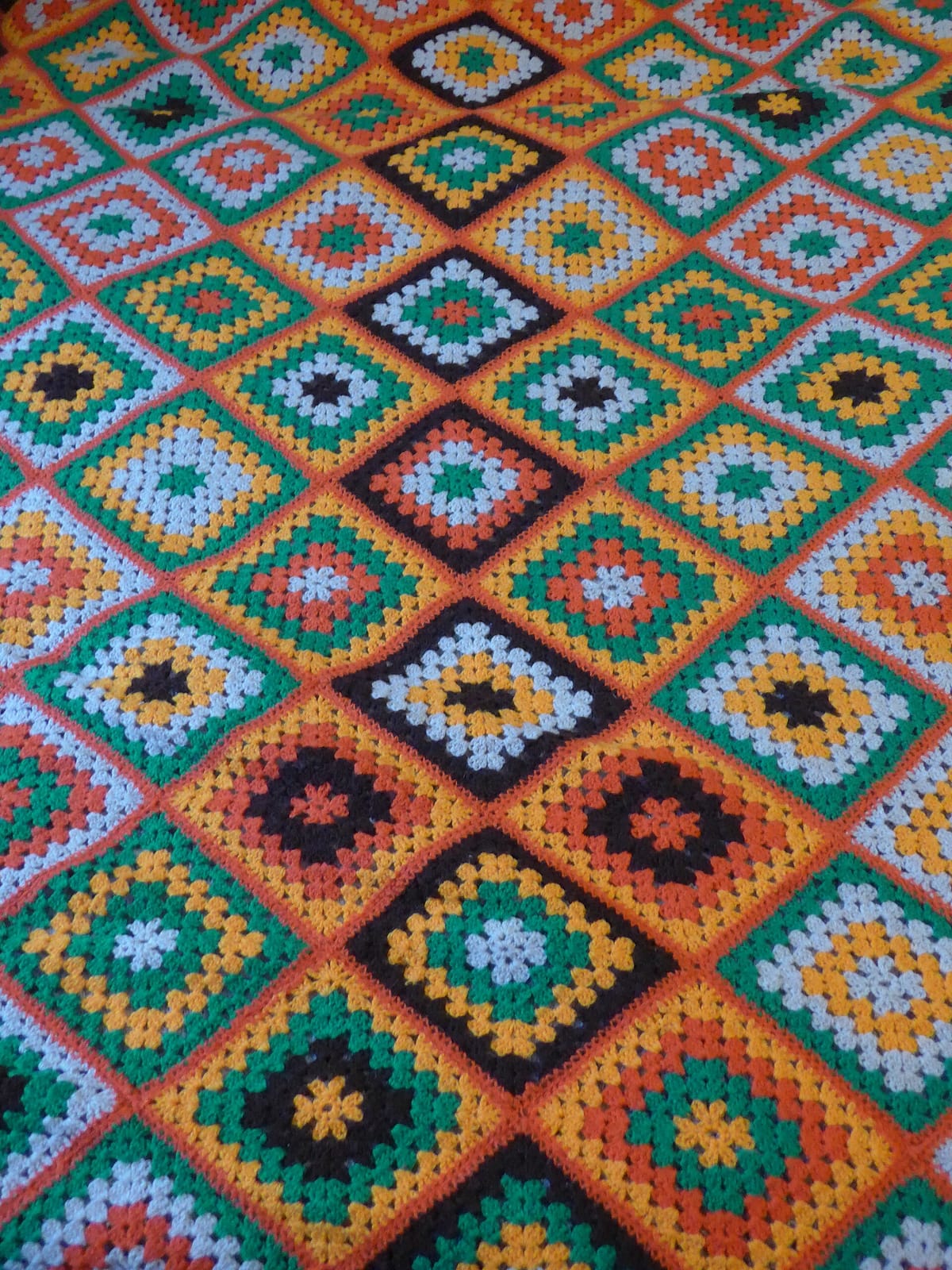 Crocheted granny square bedspread with joined squares in orange, blue and green, showing how to join granny squares