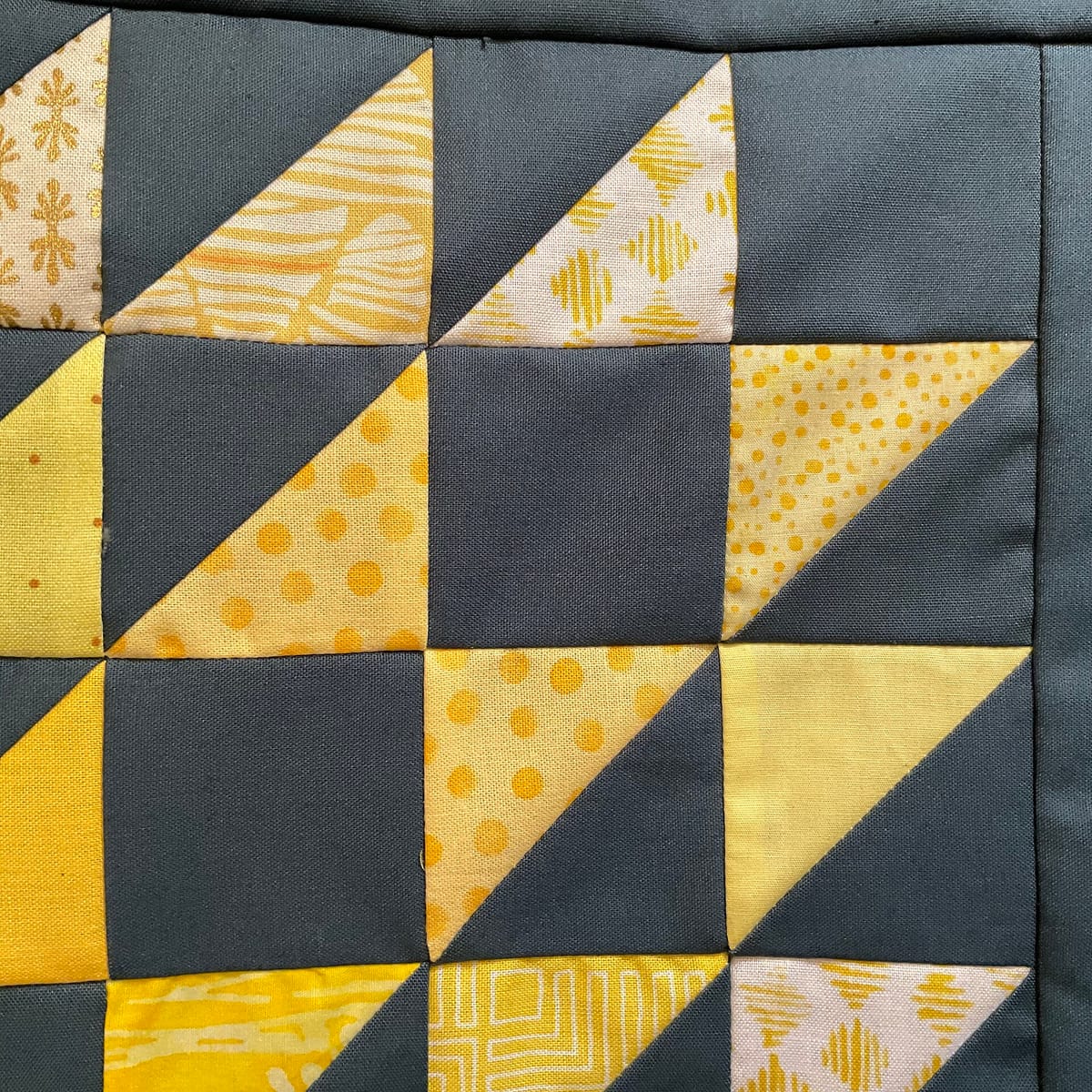 Half-square triangle patchwork in yellow prints and dark gray, for the half-square triangle calculator